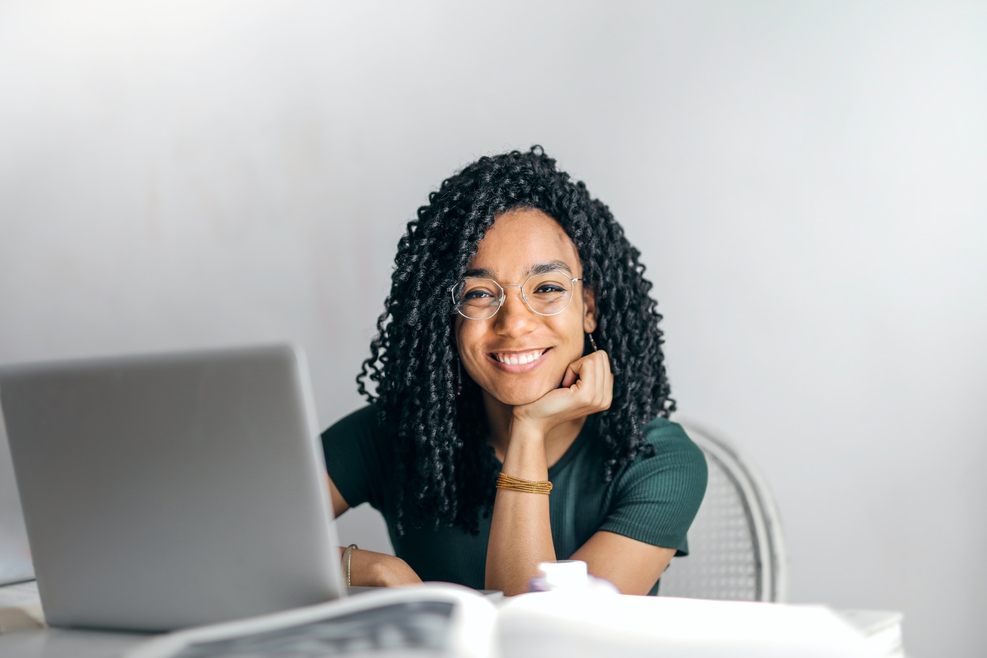 happy-ethinic-woman-sitting-at-table-with-laptop